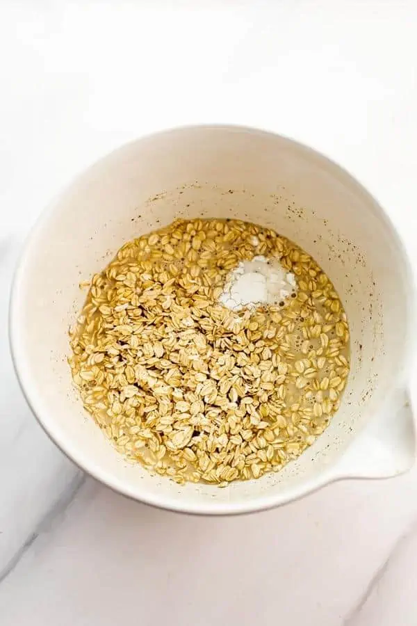 Rolled oats and baking powder in white bowl.