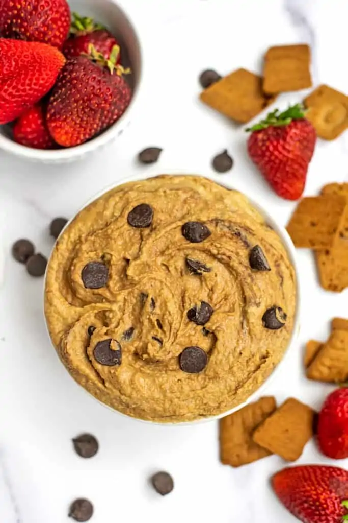 Bowl filled with cookie dough hummus, cookies and strawberries around the bowl.