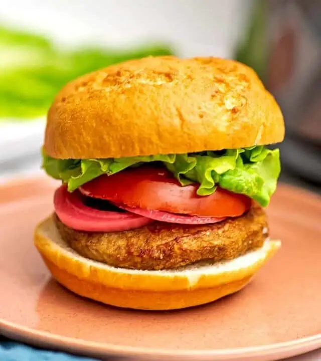 Air fryer frozen turkey burger with lettuce, tomato and pickled onions on burger.