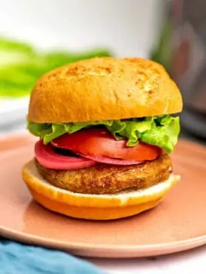 Air fryer frozen turkey burger with lettuce, tomato and pickled onions on burger.