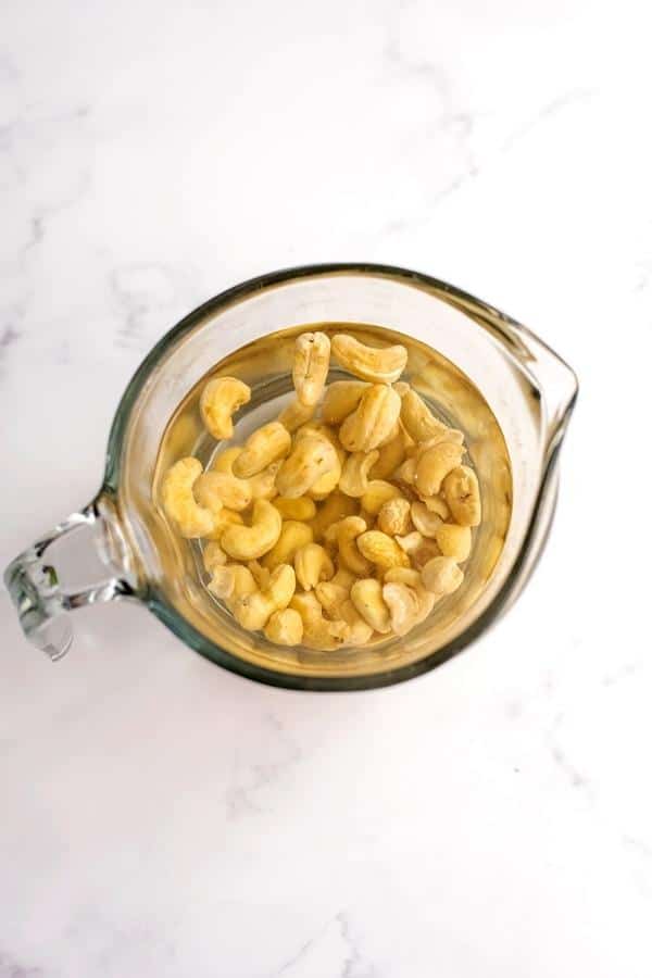 Cashews being soaked in a glass measuring cup.
