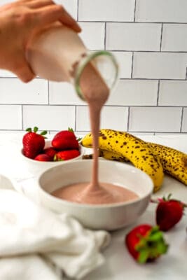 Strawberry banana smoothie being poured into a bowl.