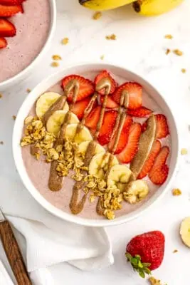 Strawberry banana smoothie bowl with almond butter drizzled on top.