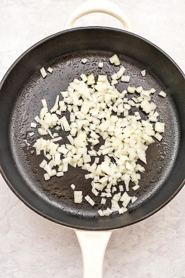 Chopped white onions in a cast iron skillet.