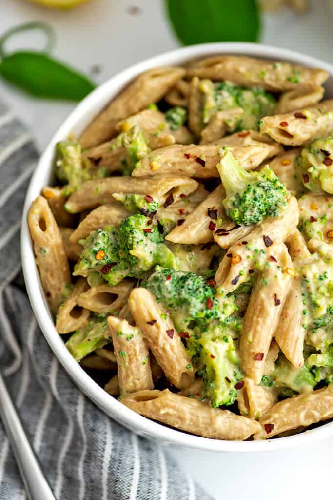 Creamy broccoli pasta with red pepper flakes on top.