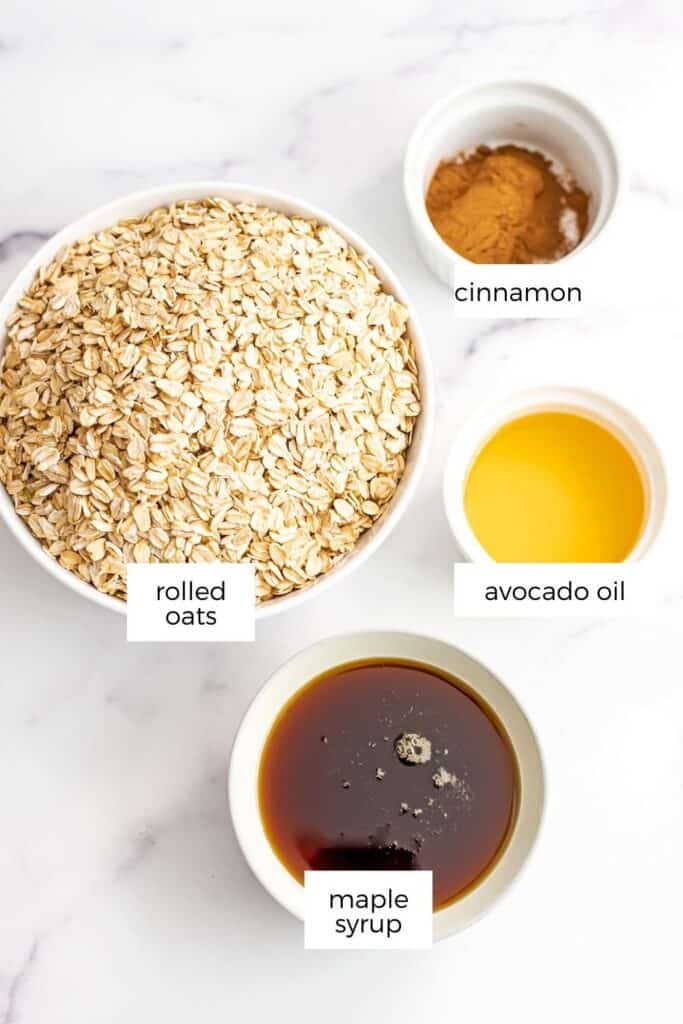 Ingredients to make vegan granola in bowls on marble countertop.