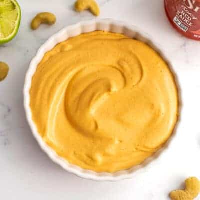 Vegan sriracha mayo in a ramekin, cashews around the bowl.