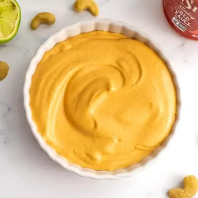 Vegan sriracha mayo in a ramekin, cashews around the bowl.