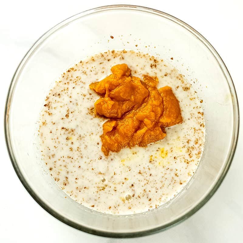 Ground flax, milk, and pumpkin puree in a glass bowl.