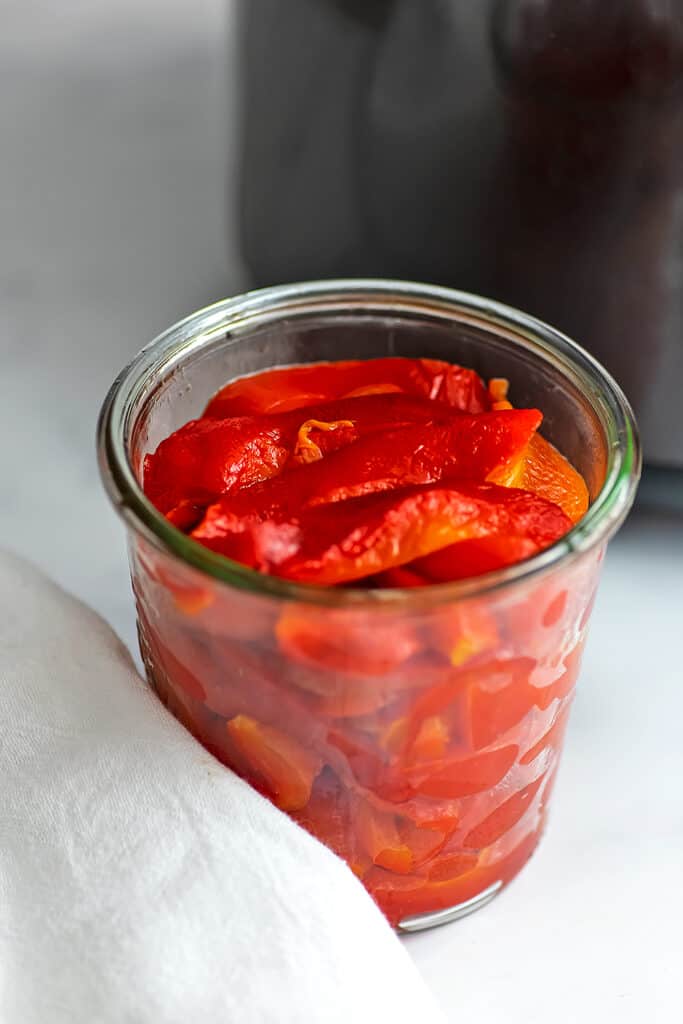 Glass jar of roasted red peppers cooked in the air fryer.