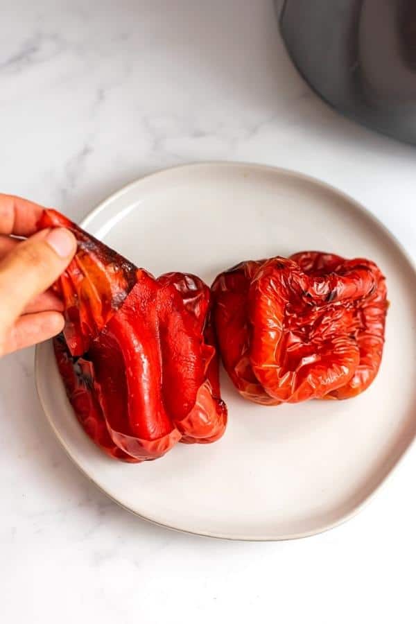 Hand peeling the skin off the air fryer roasted red peppers.