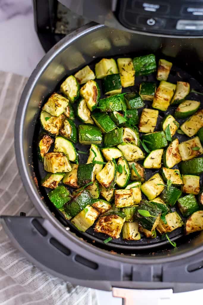 Air fryer basket filled with roasted zucchini.