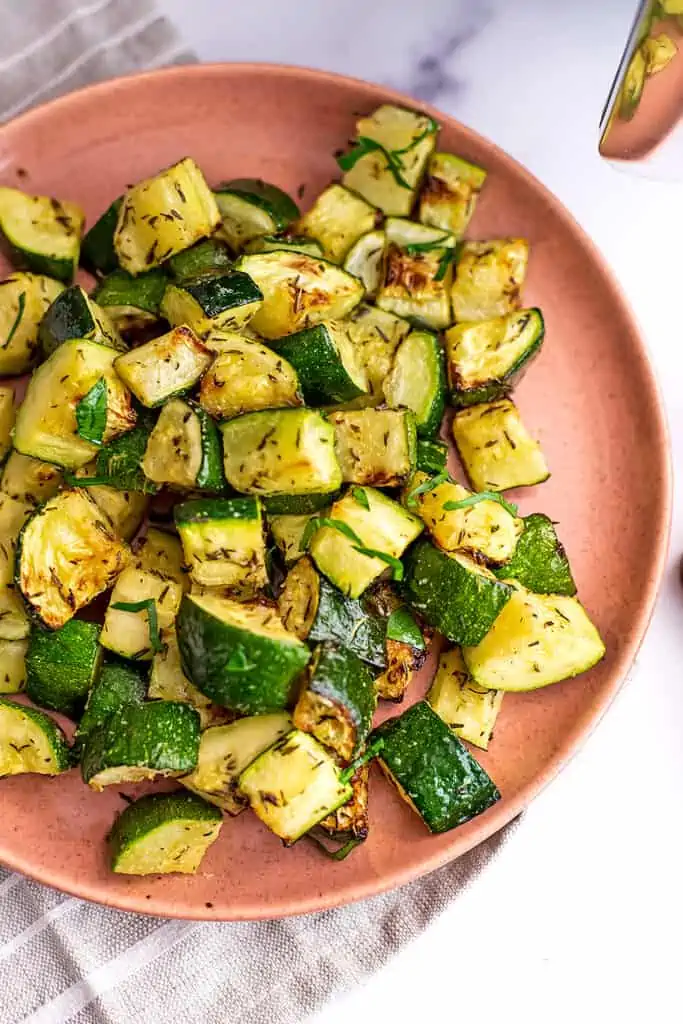 Pink plate filled with air fryer roasted zucchini.