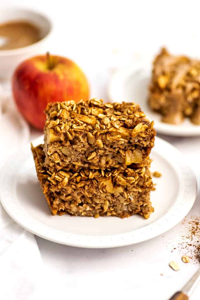 Two slices of apple oatmeal bars stacked on a white plate.