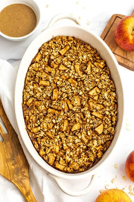 Apple baked oatmeal in a casserole dish with apples on the side.