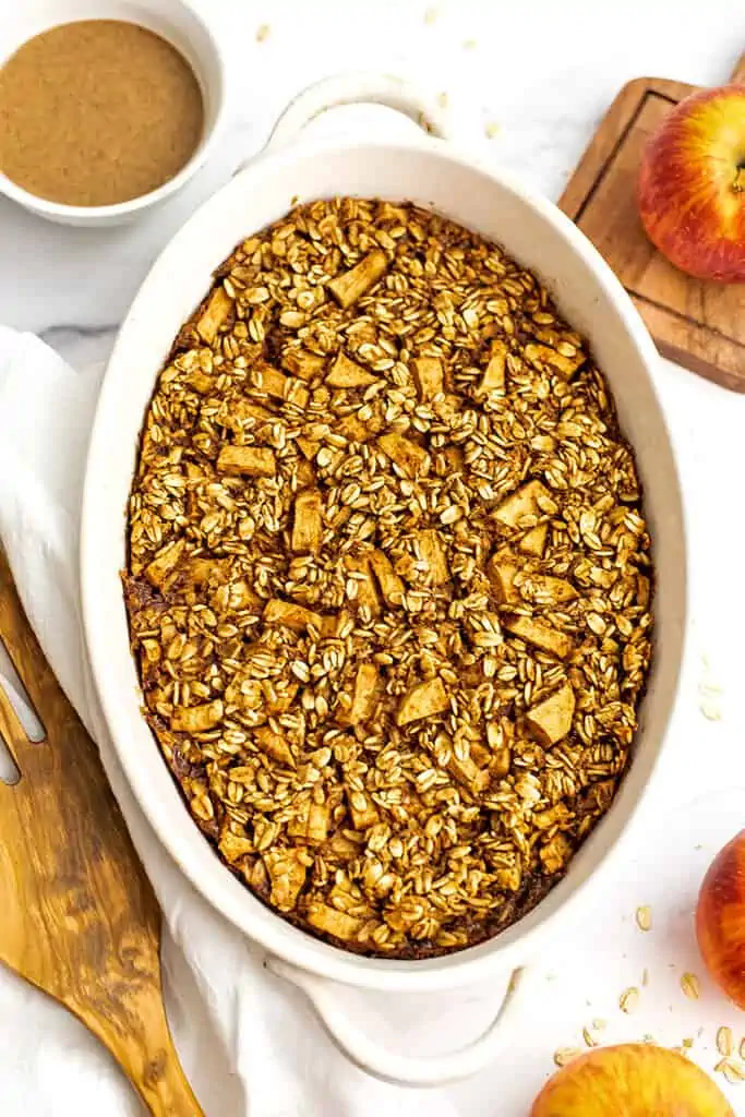 Apple baked oatmeal in a casserole dish with apples on the side.
