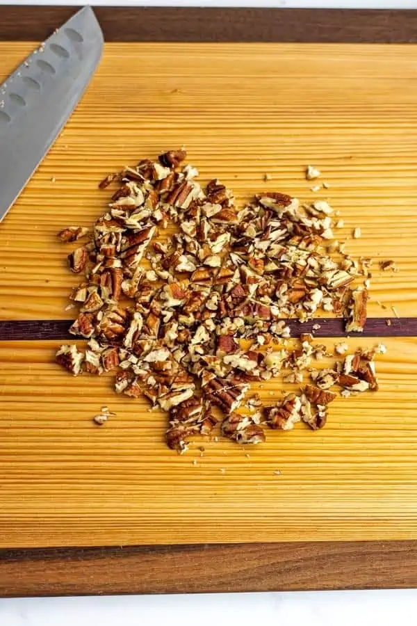 Pecans chopped on a wooden cutting board.