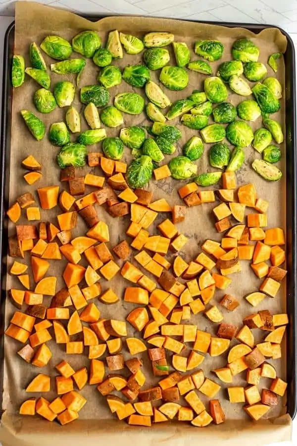 Brussel sprouts and sweet potatoes on a large sheet pan.