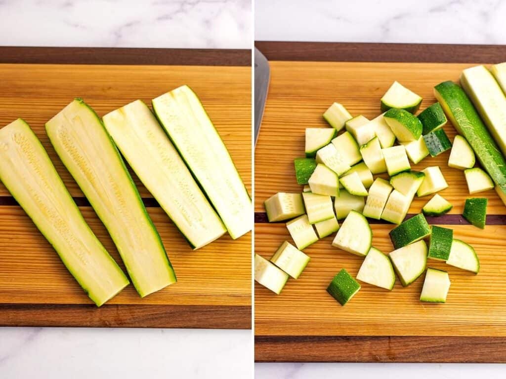 Zucchini cut in half then into cubes on a wood cutting board.