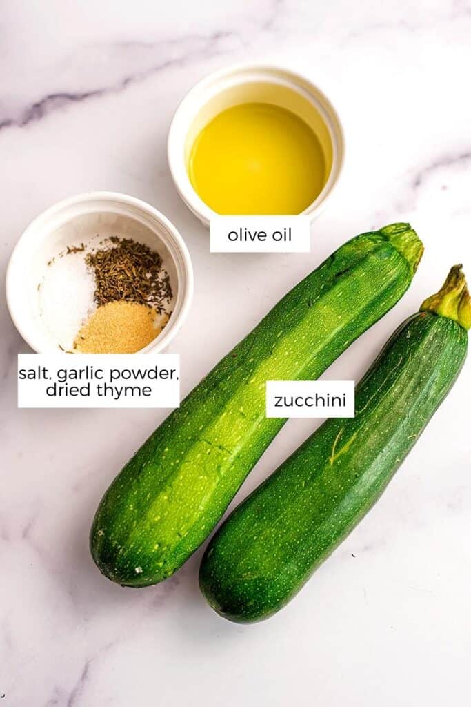 Ingredients to make air fryer roasted zucchini on a marble countertop.