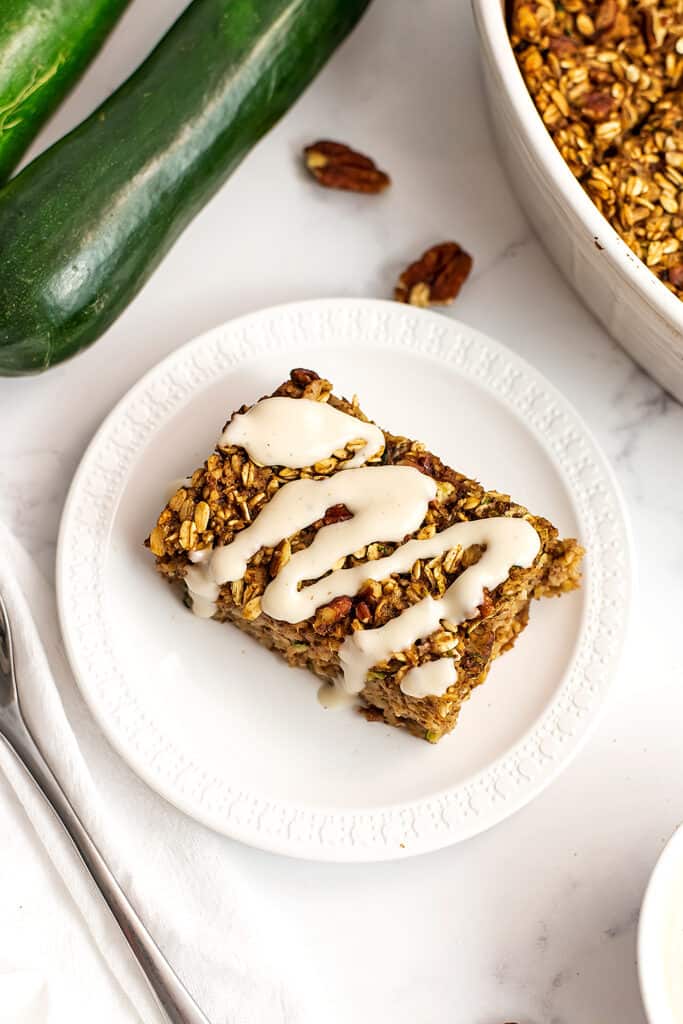 Maple yogurt frosting drizzled over a slice of zucchini oatmeal bake.