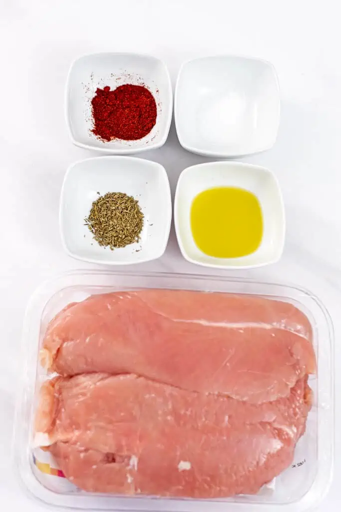 Ingredients to make juicy oven baked chicken on a marble countertop.