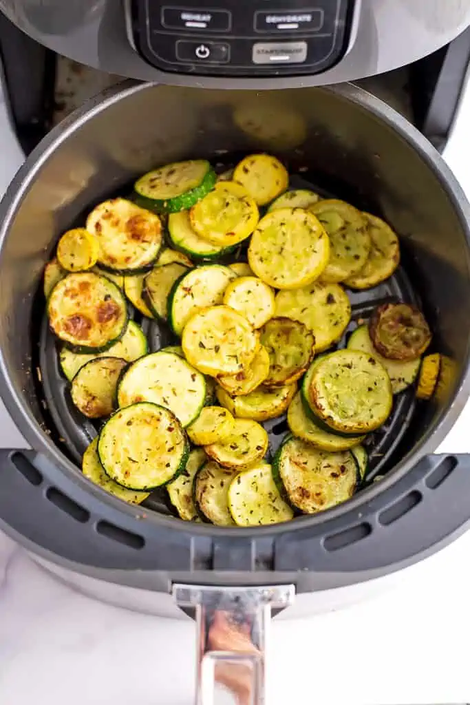 Air fryer basket filled with roasted zucchini and squash.