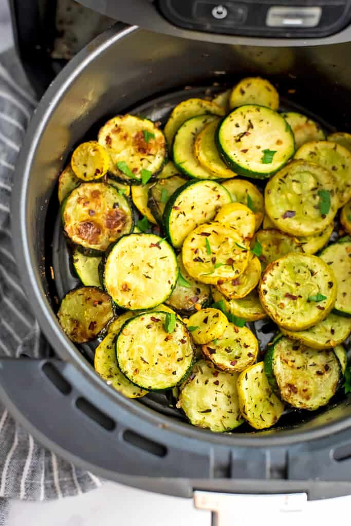 Squash and zucchini in air fryer basket after cooking.