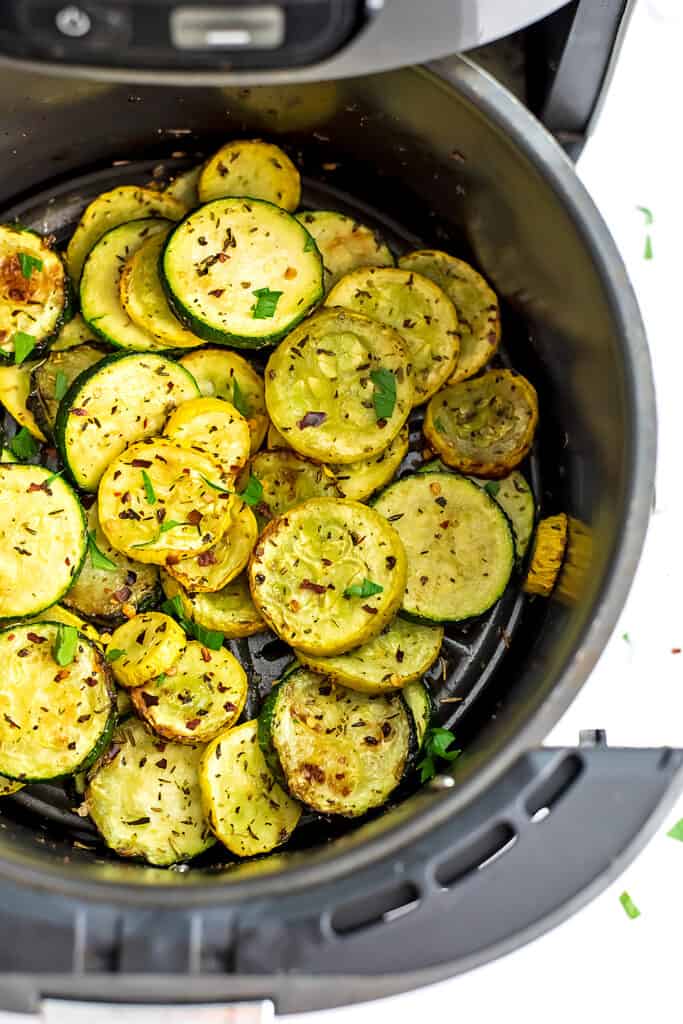 Yellow squash and zucchini slices in air fryer basket.