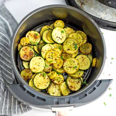 Air fryer basket filled with zucchini and squash.