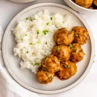 Chicken sweet and sour meatballs with jasmine rice on white plate.