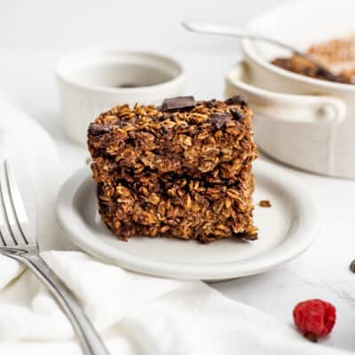 Baked oatmeal slices stacked on a white plate.