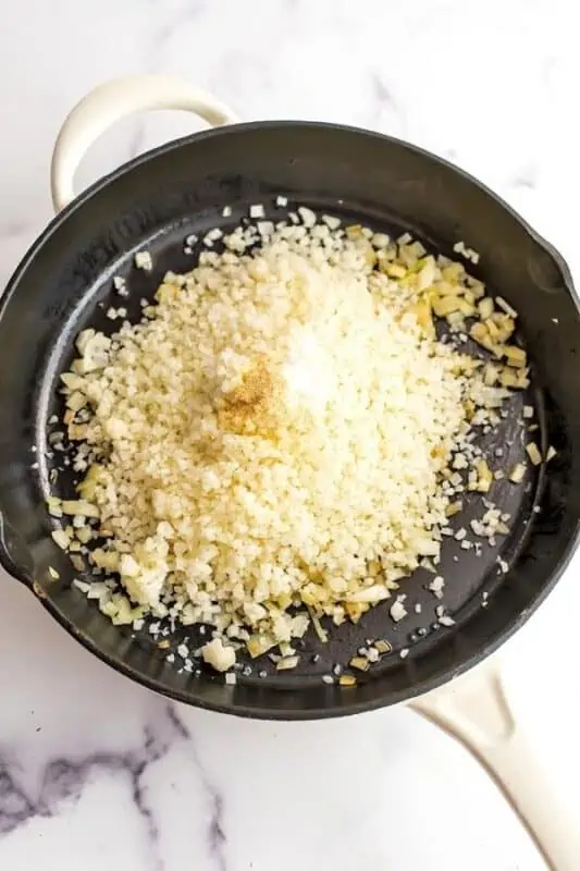 Frozen cauliflower rice added to the skillet.