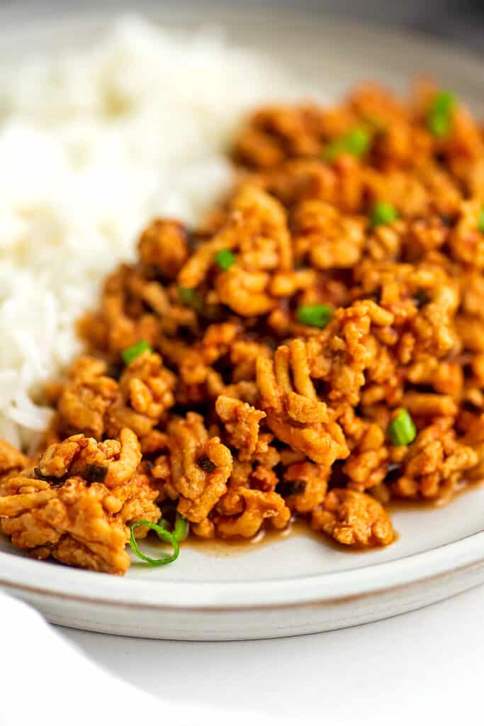 Sloppy joes with ground chicken on white plate with rice in the background.