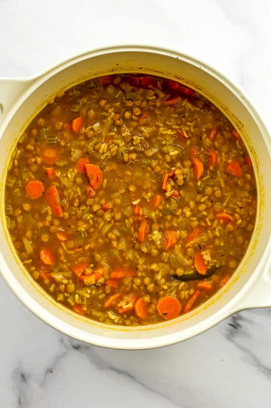 lentil brown rice soup in white bowl before adding frozen veggies. 