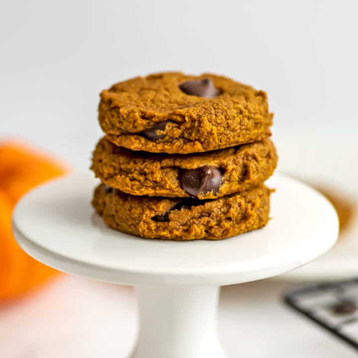 three pumpkin oat flour cookies stacked on a pedestal.
