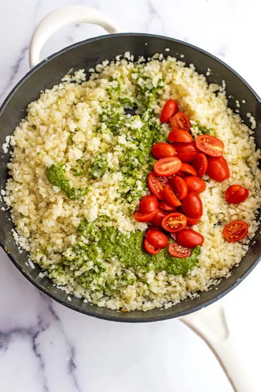 Cast iron skillet with cauliflower rice, pesto and sliced tomatoes.