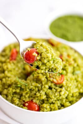 Pesto cauliflower rice in a white bowl with a spoonful of pesto cauliflower rice.