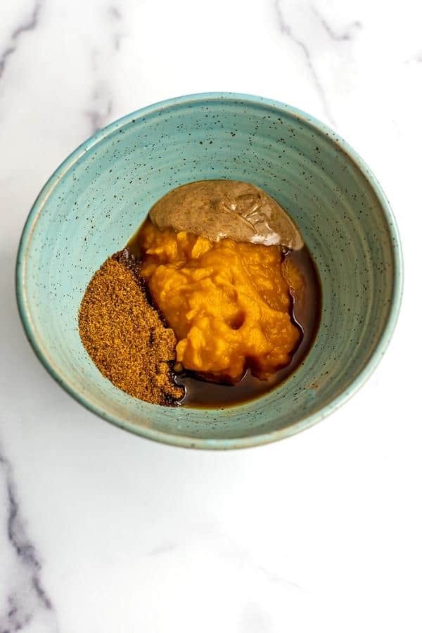 Pumpkin puree, almond butter and coconut sugar added to green bowl.