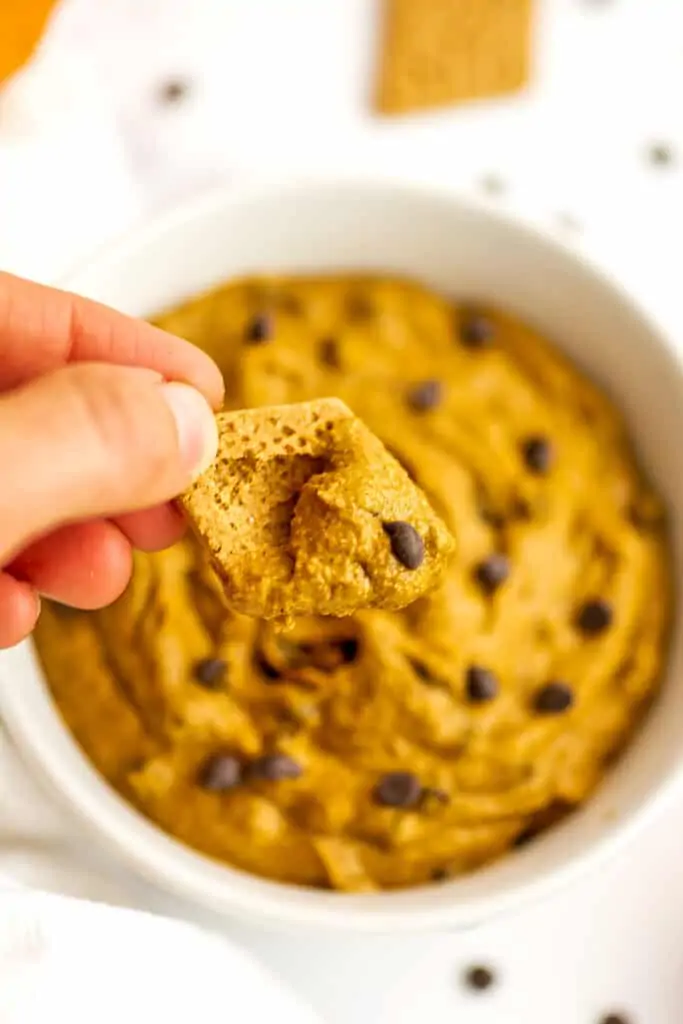 Edible pumpkin cookie dough being scooped by a graham cookie.