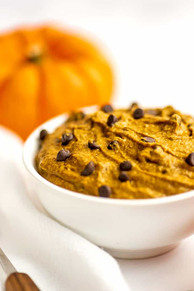bowl filled with pumpkin cookie dough, pumpkin in the background.