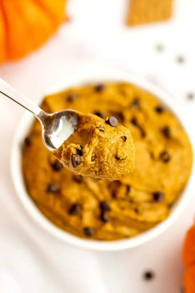 Spoonful of pumpkin cookie dough over a bowl of the cookie dough.