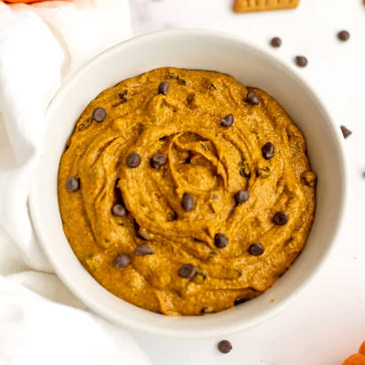 Mini chocolate chips on top of pumpkin cookie dough in a white bowl.