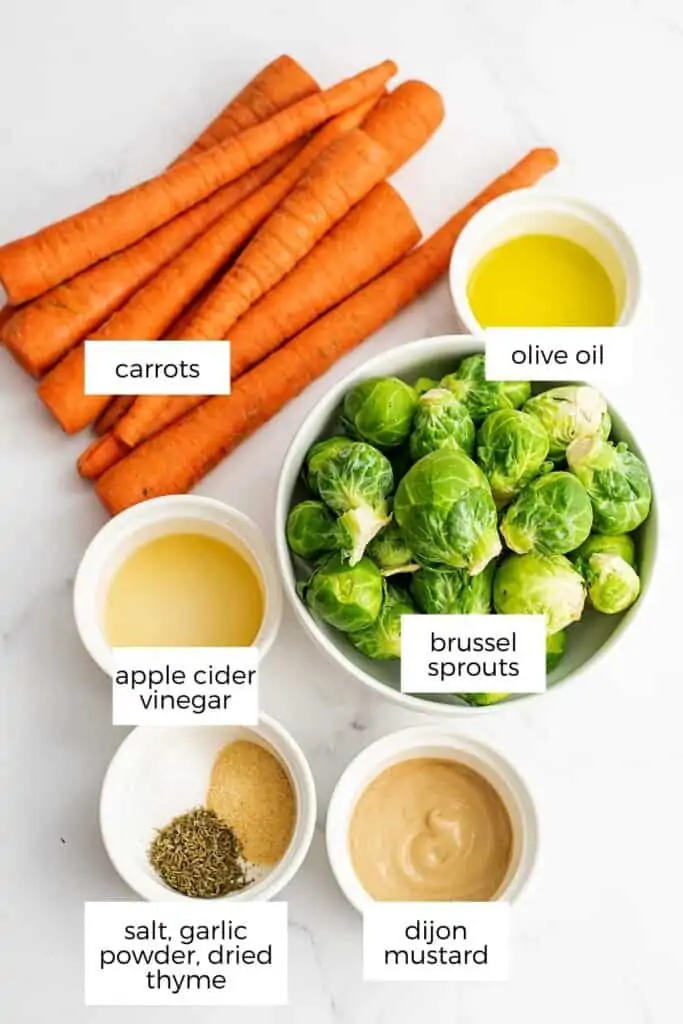 Ingredients to make brussel sprouts and carrots in white bowls.