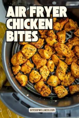 Air fryer basked filled with chicken cubes.