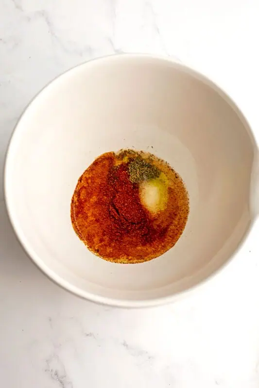 Oil, vinegar and spices in a large white bow.