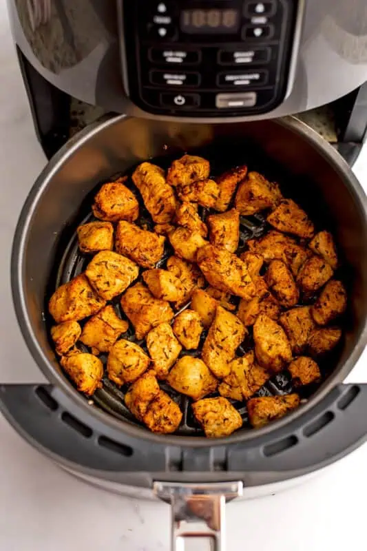 Chicken cubes in air fryer basket after cooking.