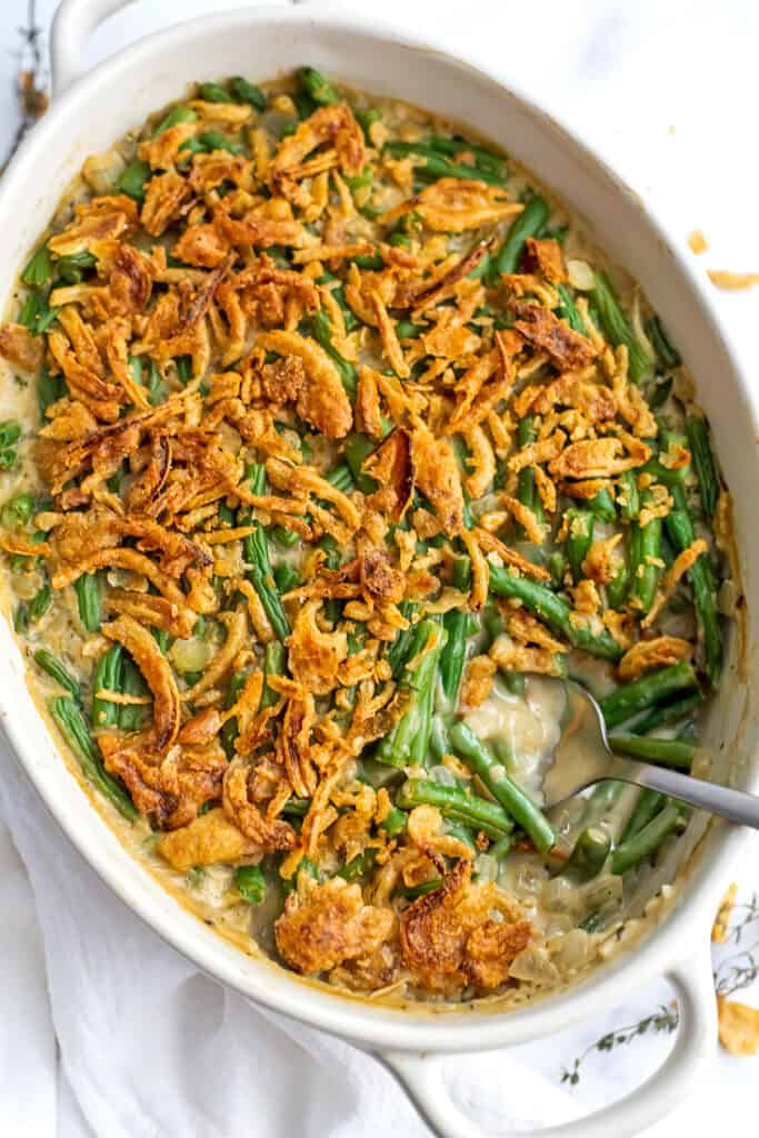Spoon in the green bean casserole where a spoonful has been removed.