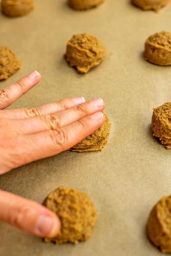 Hand pressing down gluten free sugar cookies.