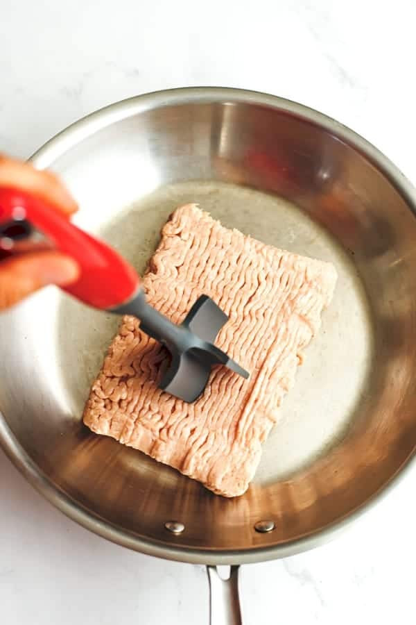 Ground beef masher breaking up raw ground chicken.